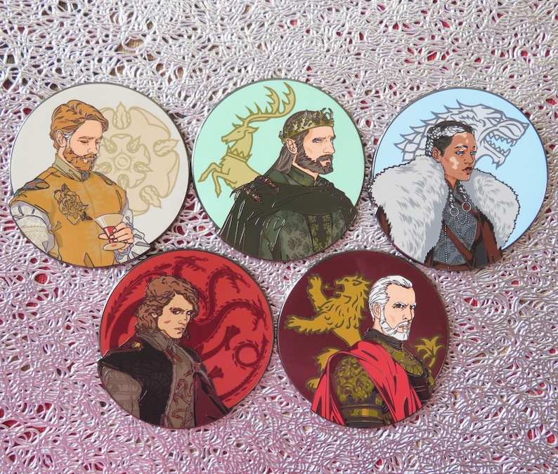 Puede incluir: Conjunto de cinco pines redondos con personajes del popular programa de televisi&oacute;n Game of Thrones. Cada pin presenta un personaje diferente con el emblema de su casa. Los pines est&aacute;n hechos de metal y tienen un acabado brillante.