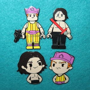 May include: Four enamel pins featuring characters from the Star Wars franchise. The pins are in a cartoon style and depict a character with a purple hat and yellow outfit, a character with black hair and a red lightsaber, a character with black hair and a black outfit, and a character with a purple hat and a yellow outfit.