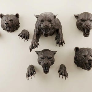 May include: A collection of dark brown wall-mounted sculptures featuring two bear heads with paws, two panther heads, and one full-bodied panther figure. Each animal is depicted with an open mouth, bared teeth, and detailed fur or skin texture.