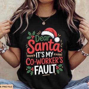 May include: Black t-shirt with the text "Dear Santa It's My Co-Worker's Fault" in red, green, and white. The design includes a Santa hat and holly accents, perfect for the holiday season.