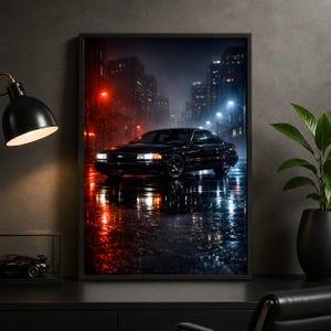 May include: A framed wall art print depicting a black saloon car parked on a wet city street at night. The scene is illuminated by contrasting red and blue ambient lighting, with tall buildings in the background and reflections on the pavement.