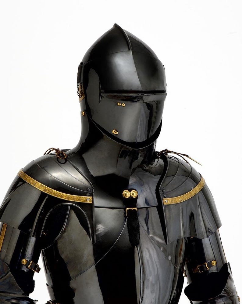 May include: A black, polished suit of armor with a helmet, shoulder guards, and chest plate. The armor has gold-colored trim and accents. The helmet has a visor and is designed to protect the face. The armor is likely made of metal.