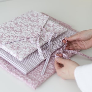 Könnte beinhalten: Ein Set aus drei Keramikbechern mit gesprenkelter, matter Oberfläche. Die Becher sind in Creme-, Hellgrau- und Dunkelgrautönen gehalten. Jeder Becher hat ein schlichtes, minimalistisches Design.