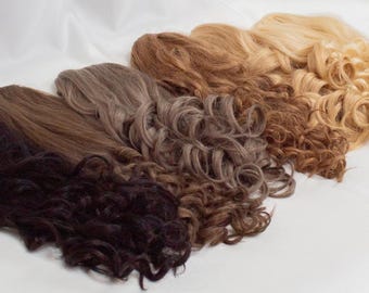 May include: A selection of wavy and curly hair extensions in shades of black, brown, and blonde. The image is set against a white background, with the word "Textures" in the bottom left corner.