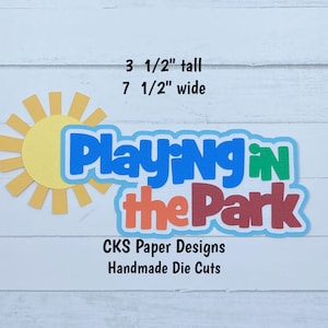 May include: A colorful die cut with the text "Playing in the Park" in a blue, green, orange, and red font. The die cut is 3 1/2 inches tall and 7 1/2 inches wide. The die cut is handmade by CKS Paper Designs.