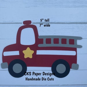 May include: A handmade die-cut paper fire truck, 5 inches tall and 7 inches wide. The truck is primarily red with white, gray, black, and yellow accents. It features a ladder, a star, and the text "CKS Paper Designs Handmade Die Cuts."