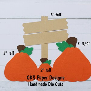 May include: Three orange paper pumpkins with green stems and brown tops, a brown paper sign with the text "CKS Paper Designs Handmade Die Cuts", and the measurements 3 3/4 inches, 3 inches, 2 inches, and 5 inches.