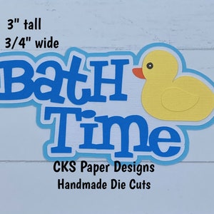 May include: Blue and white paper die cut of the words "Bath Time" with a yellow rubber ducky. The die cut is 3 inches tall and 5 3/4 inches wide.