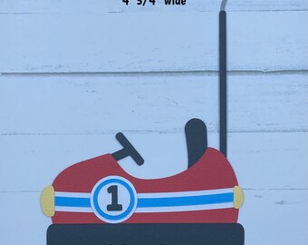 May include: A handmade die-cut paper bumper car, 6 inches tall and 4.75 inches wide. The car is red with a blue stripe, a white circle with the number 1, and black and yellow accents. The text "CKS Paper Designs Handmade Die Cuts" is at the bottom.
