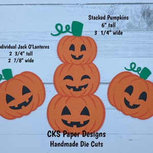 May include: Three stacked orange paper pumpkins with black smiling faces and green stems. Two individual orange paper pumpkins with black smiling faces and green stems. The text "Stacked Pumpkins 6" tall 3 1/4" wide" and "2 Individual Jack O'Lanterns 2 3/4" tall 2 7/8" wide" is written on a white wood background. The text "CKS Paper Designs Handmade Die Cuts" is written below the pumpkins.