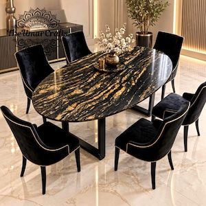 Op de afbeelding: Een ovale eettafel met een zwart en goud marmeren blad en zwarte metalen poten, omringd door zes zwarte fluwelen stoelen met gouden biezen. Een gouden vaas met witte bloemen staat op de tafel. De tekst The Umar Crafts is zichtbaar.