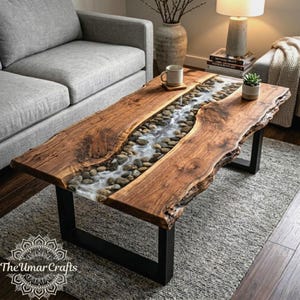 May include: A handcrafted coffee table with a unique river design. The table features a live edge wooden top with a central river of resin and stones. It has a black metal base and measures approximately 48 inches long.