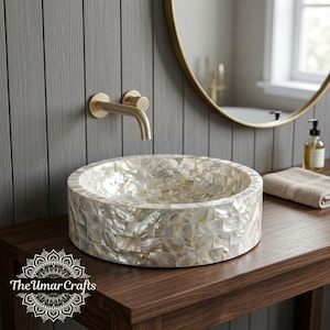 May include: A round vessel sink featuring a mosaic of iridescent mother-of-pearl tiles. The sink is paired with a wall-mounted brushed gold faucet. A logo with the text The Umar Crafts is visible in the lower left corner of the image.