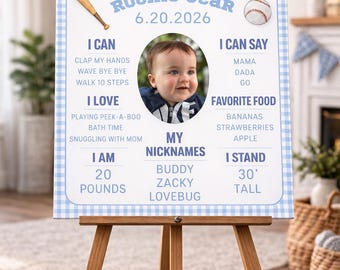 Könnte beinhalten: Ein 'Rookie Year'-Schild für ein Baby auf einer Holzstaffelei. Das Schild ist hellblau mit einem Vichy-Karo-Rand und zeigt ein Foto, Baseball-Grafiken und Text, einschließlich des Namens des Babys, Spitznamen und Lieblingsspeisen. Das Schild ist 76 cm hoch.