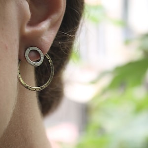 Peut inclure: Une paire de boucles d'oreilles créoles en argent avec une texture martelée. Les créoles sont à double couche, avec un cercle plus petit à l'intérieur d'un cercle plus grand.