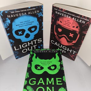 Puede incluir: Se muestran tres libros de Navessa Allen. Las portadas presentan gráficos llamativos: una calavera azul, un casco rojo y una máscara verde. Los títulos incluyen "Lights Out", "Caught Up" y "Game On". Los libros forman parte de la serie "Into Darkness".