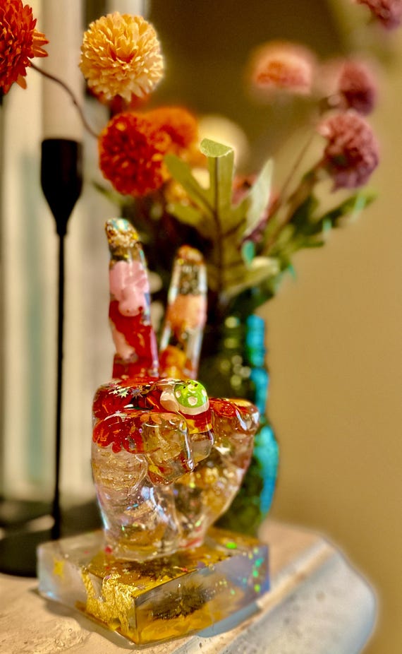A hand-sculpted resin peace sign hand — part pop-art desk sculpture, part conversation-starter that walks the line between office decor and gallery piece.