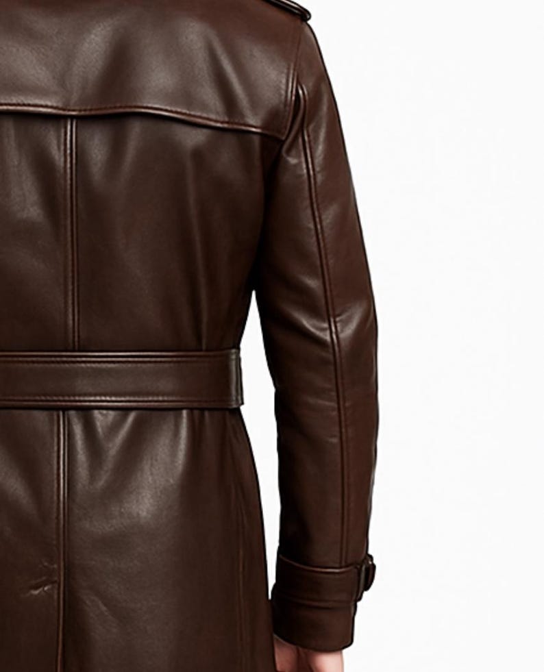 May include: A brown leather trench coat with a belted waist and a notched collar. The coat features a classic design with a buttoned cuff and a back vent. The leather appears smooth and has a slight sheen.