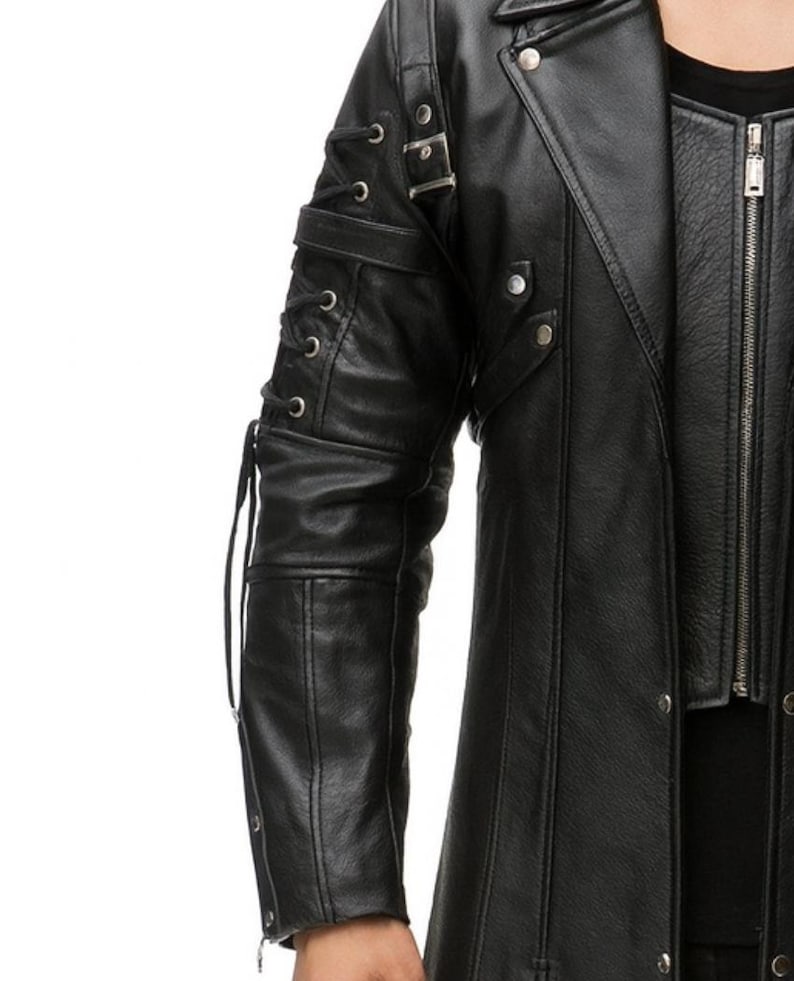 May include: A black jacket featuring a long-sleeve design with decorative lace-up detailing along the outer arm, silver-toned metal buckles, and studs. The garment includes a front zipper closure and a structured collar with visible seams.