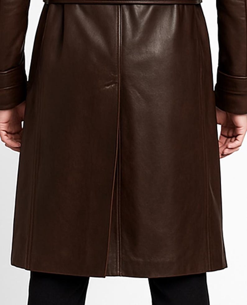 May include: A brown leather trench coat with a belt. The coat has long sleeves and a button closure. The back of the coat has a vent at the bottom. The coat is made of a smooth, shiny leather material.