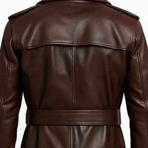 May include: A brown leather trench coat with a belted waist and a notched collar. The coat features epaulets on the shoulders and a back yoke. The leather has a smooth, polished finish, and the coat appears to be well-tailored.