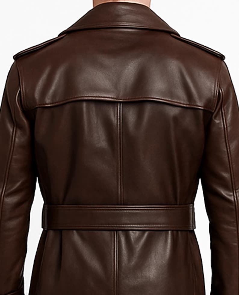 May include: A brown leather trench coat with a belted waist and a notched collar. The coat features epaulets on the shoulders and a back yoke. The leather has a smooth, polished finish, and the coat appears to be well-tailored.