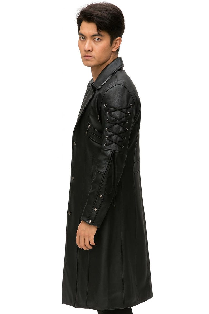 May include: A black long coat featuring a structured collar and a front button closure. The sleeves are detailed with black lace-up cord accents through metal eyelets, complemented by a series of silver-toned metal studs along the forearm area.