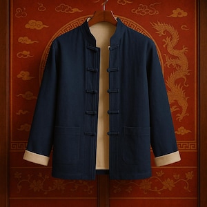 Peut inclure: Veste bleu marine avec col officier et fermetures à bascule. La veste a une doublure et des poignets beiges. Elle est suspendue à un cintre en bois sur un fond rouge avec des accents dorés. La veste a deux poches avant.