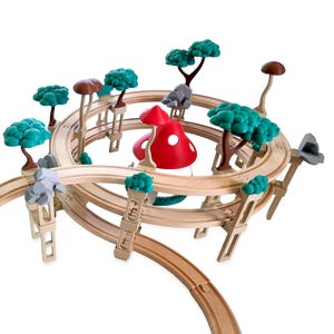 Könnte beinhalten: Holzspielzeug-Eisenbahn mit einem skurrilen Waldthema. Das Set enthält eine gewundene Strecke, Bäume mit grünem Laub, graue Felsformationen und einen großen roten Pilz mit weißen Punkten. Die Strecke ist aus hellbraunem Holz.