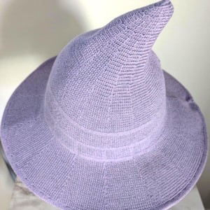 Peut inclure: Un chapeau de sorcière de couleur lavande avec un large bord et une couronne pointue. Le chapeau est fait d'un matériau tissé et comporte une bande décorative autour de la base de la couronne. Parfait pour Halloween ou les fêtes costumées.