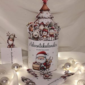 Könnte beinhalten: Weißer Adventskalender mit Christbaumaufsatz und Illustrationen von Weihnachtsmann, Rentieren und verschiedenen Zeichentrickfiguren. Der Kalender enthält 24 süße Botschaften und Zierornamente.