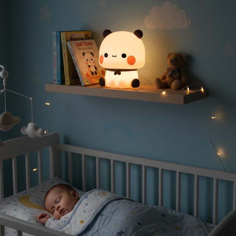 May include: A glowing panda-shaped night light sits on a wooden shelf above a baby's crib. The lamp has a white body, black ears and feet, and orange cheeks. A teddy bear and books are also on the shelf. The baby is sleeping in the crib.