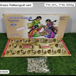 May include: A brass Pallanguli set, featuring a table-type game with small bowls and rectangular compartments. The set includes a box with illustrations of children playing the game, and a bag of white shells. The box measures 1 inch high, 13 inches long, and 7 inches wide.