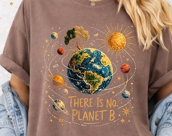 May include: A brown t-shirt featuring a graphic of the Earth surrounded by various planets, stars, and a tree. The text "There Is No Planet B" is printed in gold lettering below the central Earth illustration, set against a celestial background.