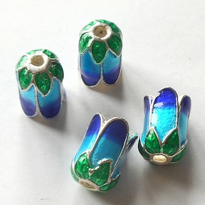 May include: Four enameled beads in a floral design. The beads are blue and turquoise with green leaf accents and silver-colored metal trim. The beads are shaped like flower buds.