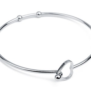 Könnte beinhalten: Ein silbernes Armkettchen mit einem Herz-Anhänger und drei kleinen Perlen.
