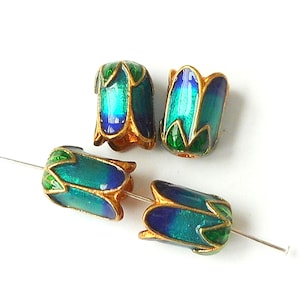 May include: Four blue, green, and gold enamel beads with a floral design. The beads are strung on a thin wire.