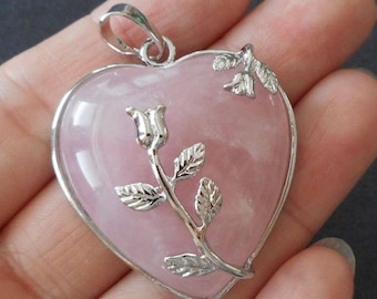 May include: A pink heart-shaped pendant with a silver rose design. The pendant is made of rose quartz and has a silver bail for attaching to a necklace.