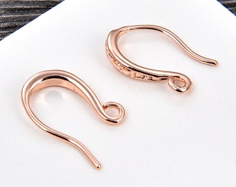 May include: Two rose gold earring hooks. One hook is plain and the other has a textured design.