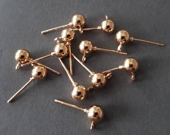May include: A group of 10 gold-toned earring posts with round ball tops. The posts are made of metal and have a smooth finish.