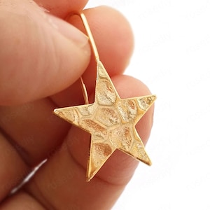 May include: Gold star-shaped dangle earrings with a textured surface.