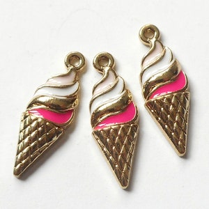 May include: Three gold-tone ice cream cone charms with pink and white enamel detailing. The charms are ideal for adding a touch of whimsy to jewellery or crafts.