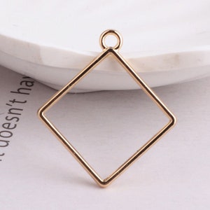 May include: Gold-toned metal pendant with a square frame and a loop at the top.