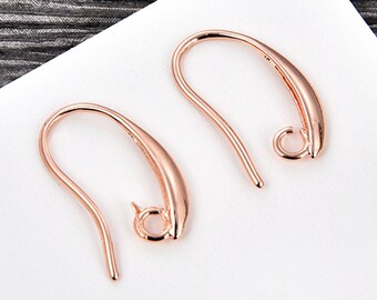 May include: Two rose gold earring hooks. The hooks are made of metal and have a smooth, curved shape.