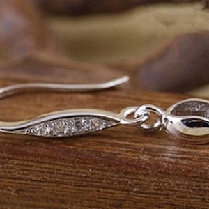 May include: Silver earring hook with a small, clear crystal embellishment and a loop at the end.