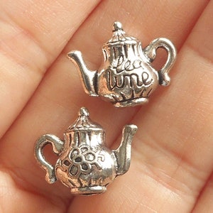 Peut inclure: Deux breloques en forme de théière argentées avec les mots "tea time" sur l'une et un motif floral sur l'autre.