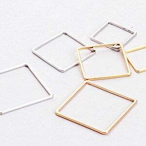 May include: Five different sized metal hoops, two silver and three gold, in the shape of a square.