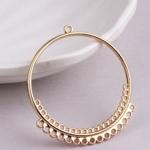 May include: Gold-toned metal hoop earring with a decorative scalloped edge. The hoop is open at the top and has a small loop for attaching to an earring hook.