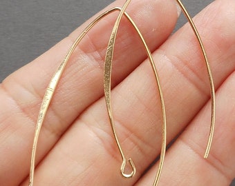 May include: Two gold-toned, wire, earring hoops with a slightly curved shape. The hoops are open at the top and have a small loop at the bottom.