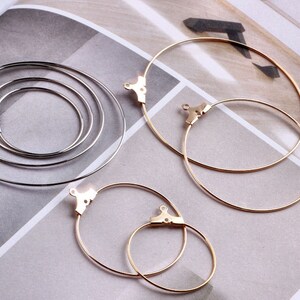 May include: Set of four hoop earrings, two gold and two silver. The gold hoops are in different sizes, one larger than the other. The silver hoops are all the same size.